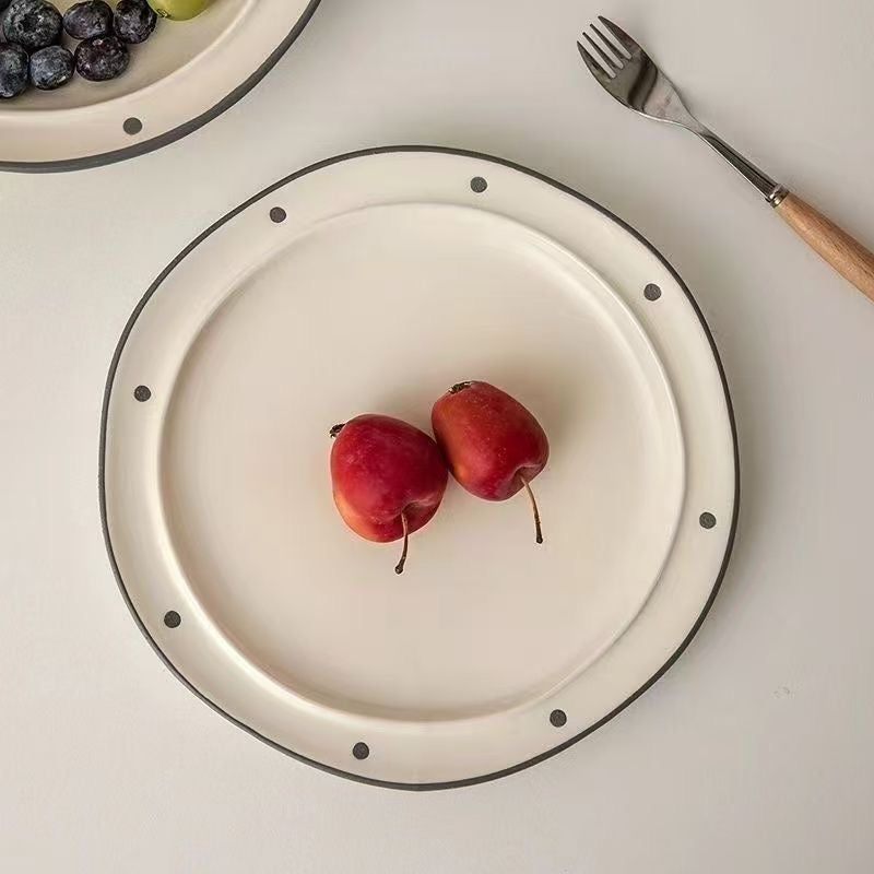 Two red apples on a white plate with a fork and bowl of blueberries in the background.