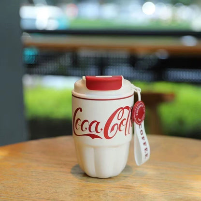 Two Coca Coffee Tumblers, one white and one red, with a 'Coca Coffee' print on them, being held in front of a Marshall speaker.